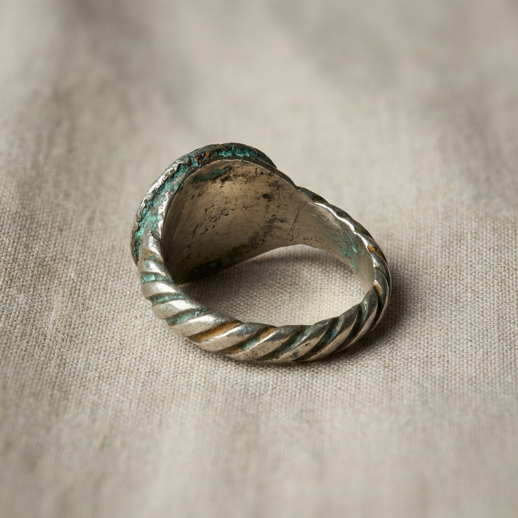 Full frame studio photo of an antique viking ring with green blue patina on neutral linen background in Aurora Antiqua palette background #ede7da accents #ae8339