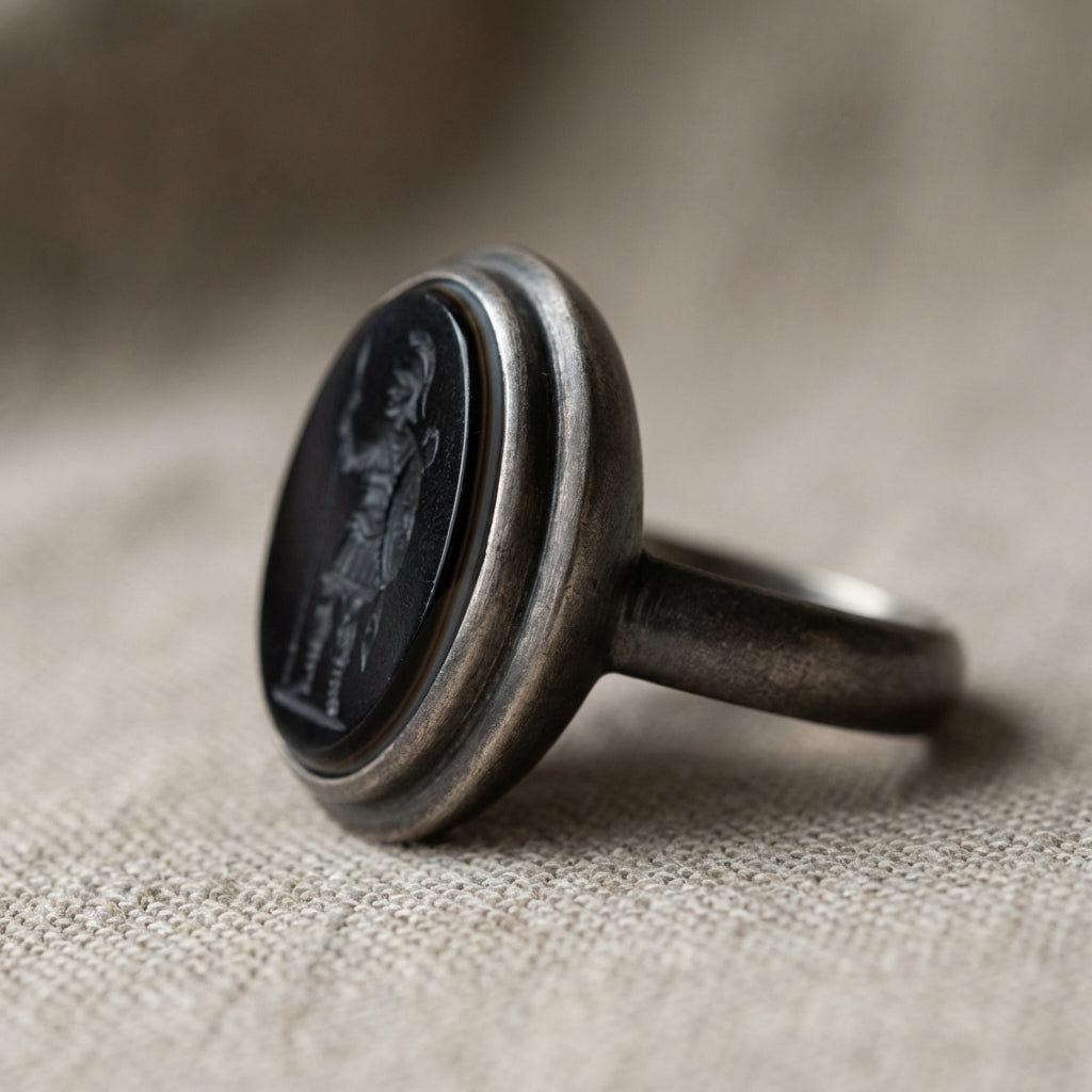 Close up of black onyx roman soldier ring showing dark intaglio bezel profile and banded stone edge on neutral linen backdrop in Aurora Antiqua palette