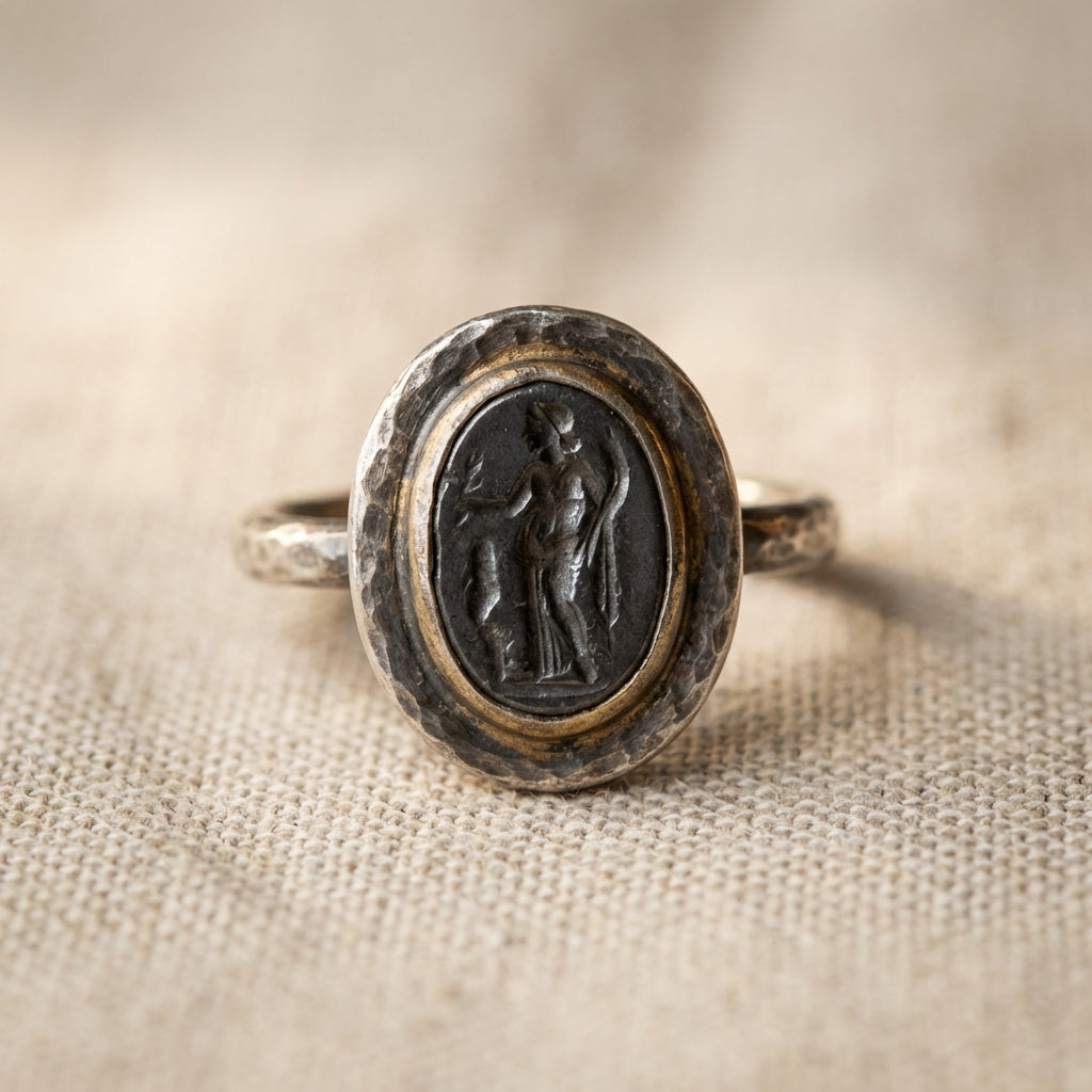 Close cropped studio photo of hematite roman soldier ring showing dark hematite intaglio set in ancient silver hoop on neutral linen with visible bezel detail and antique patina