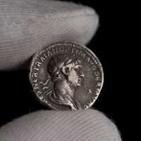 Roman silver denarius of Trajan held for size reference.