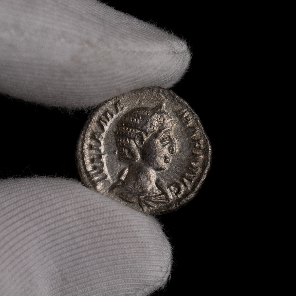 Roman silver denarius of Julia Mamaea held for size reference.