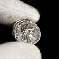 Roman silver denarius of Antoninus Pius shown in hand for context.