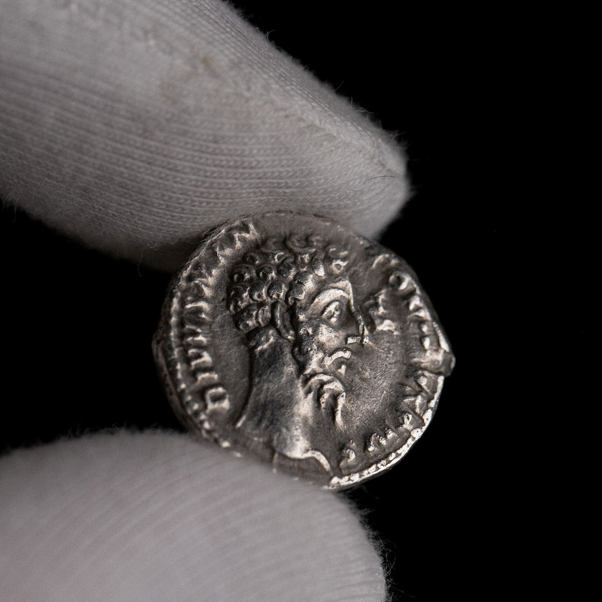 Roman silver denarius of Divus Marcus Aurelius (under Commodus) shown in hand for context.