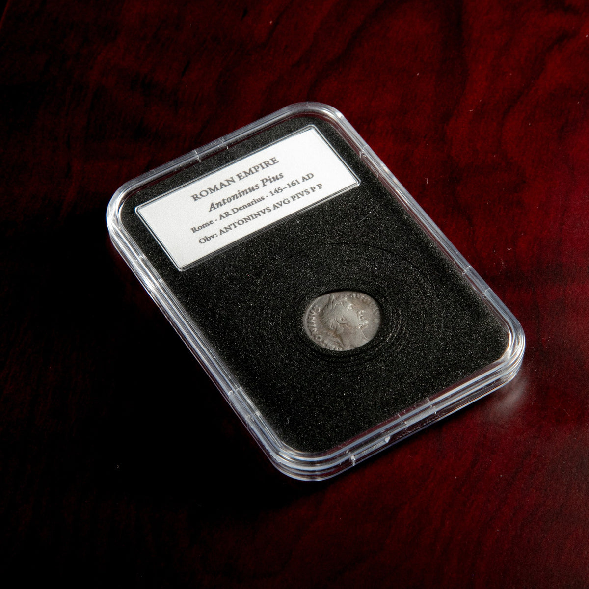 Roman silver denarius of Antoninus Pius in protective slab with catalog label.