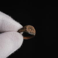 Medieval bronze signet ring Falco held in gloved hand, close detail of incised bezel device