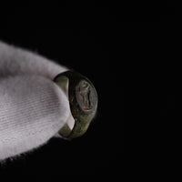 Roman bronze signet ring Numerius Faber held in gloved hand, deity intaglio visible on oval bezel