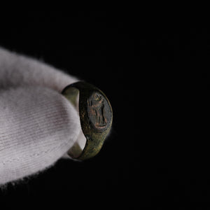 Roman bronze signet ring Numerius Faber held in gloved hand, deity intaglio visible on oval bezel