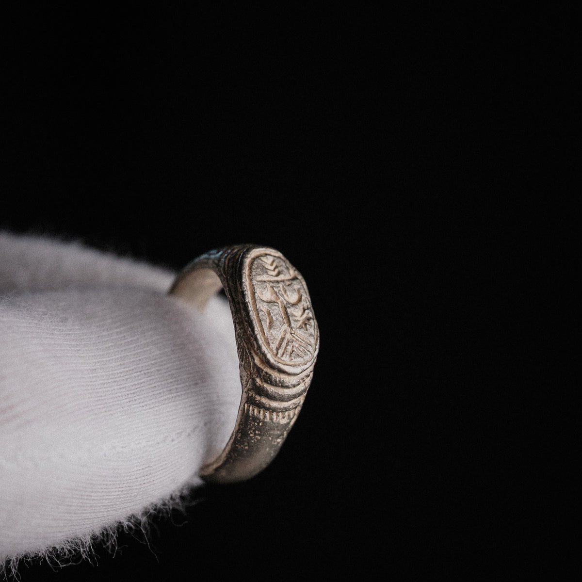 Medieval silver signet ring Merrick, three-quarter view showing engraved merchant's mark bezel