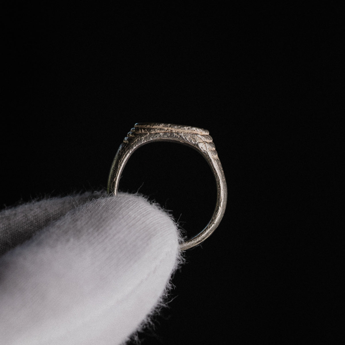 Medieval silver signet ring Merrick, profile view showing D-section hoop and notched shoulders