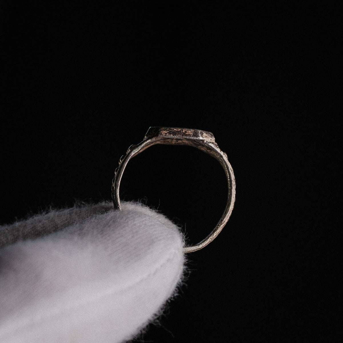 Profile view of Vasilisa silver signet ring showing flat bezel and tapered hoop against dark backdrop