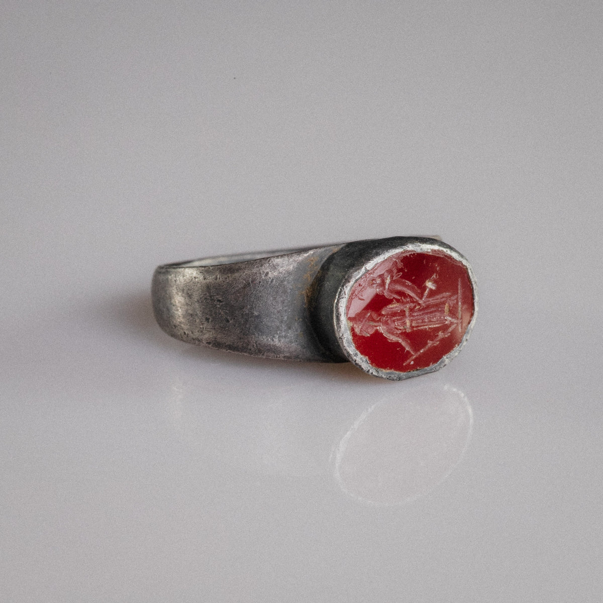 Roman silver ring Sereia three-quarter view showing raised oval garnet bezel and engraved figure
