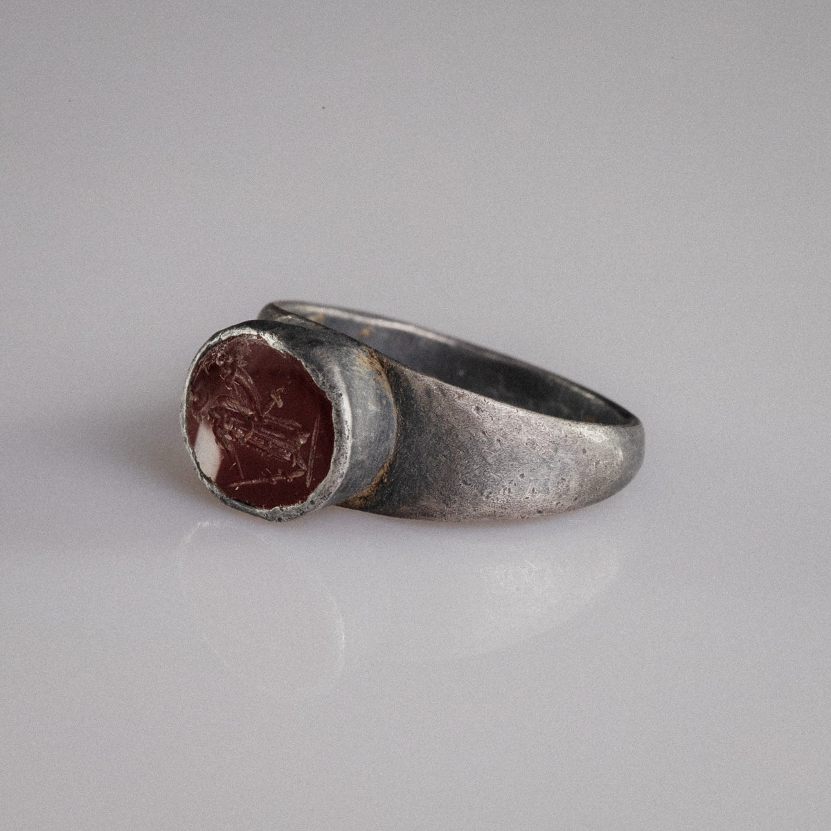 Close-up of Roman silver ring Sereia held in gloved hand, garnet intaglio detail visible