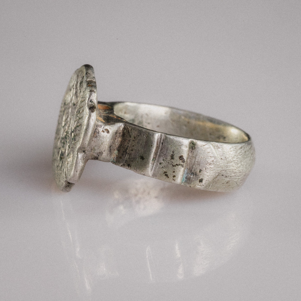 Three-quarter view of Florian medieval silver ring showing engraved sexfoil bezel and faceted shoulders