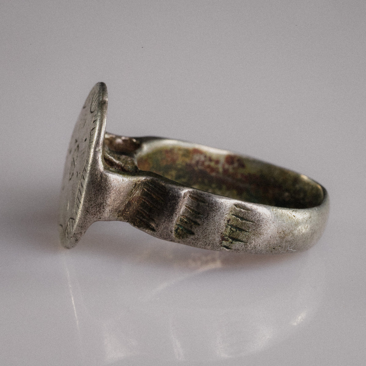 Angled side view of medieval silver signet ring Stavros with incised shoulder grooves