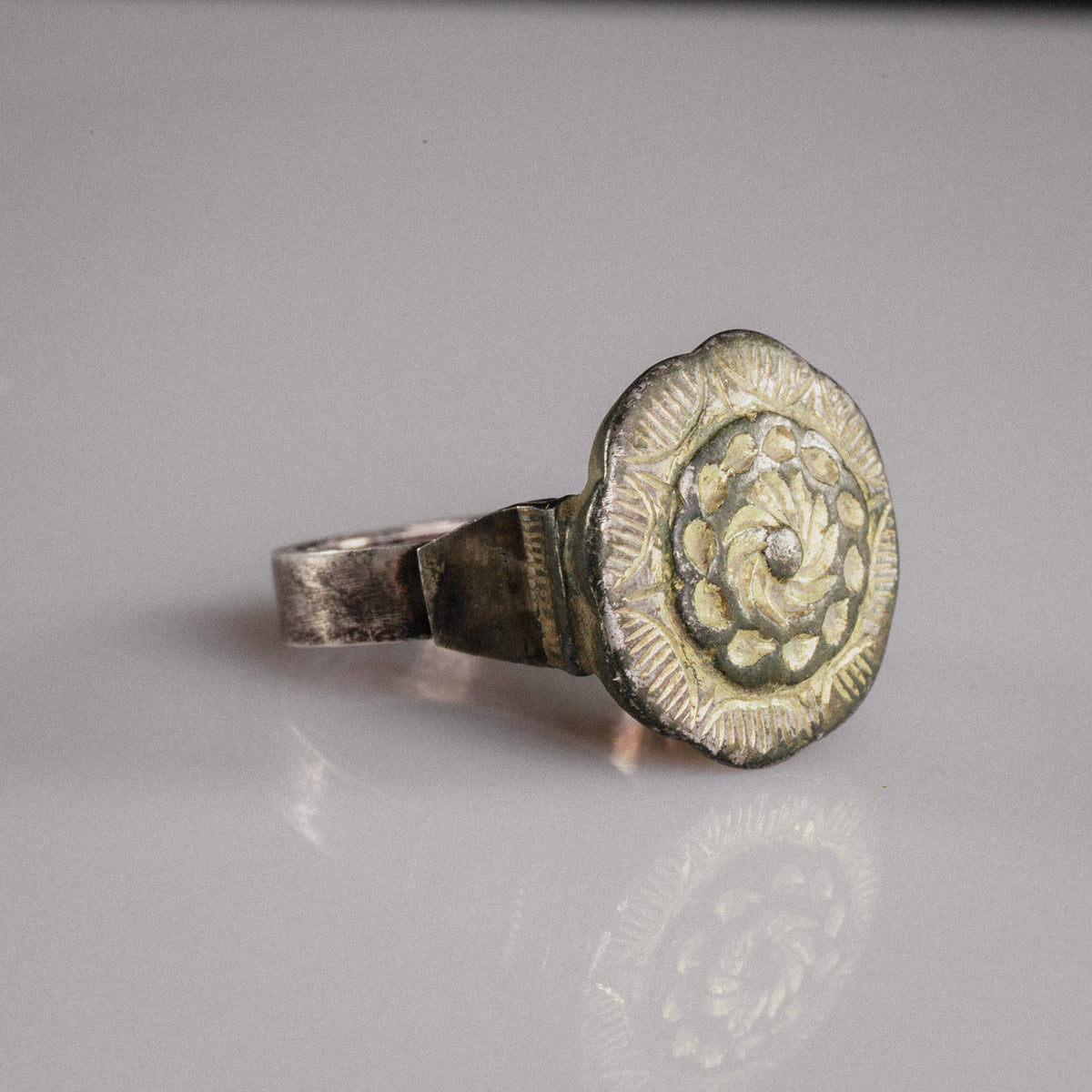 Islamic silver ring Gulizar showing gilt rosette bezel and stepped shoulder in three-quarter view