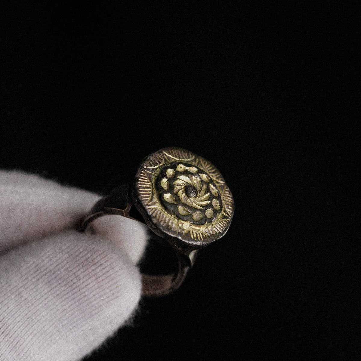 Islamic silver ring Gulizar held in gloved hand, close view of parcel-gilt bezel
