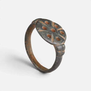 Byzantine bronze ring 'Heliona' shows the holes and incised strokes on its circular bezel at an angle.