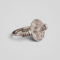 Angled view of Roman silver ring Veneria showing engraved plate fixed between coiled shoulders