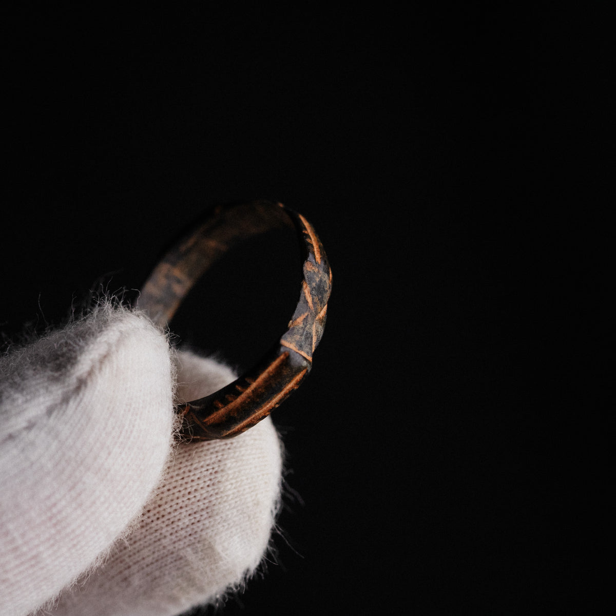 Angled view of medieval bronze ring Aldric revealing hatched panel decoration and wear