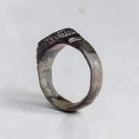 Angled view of medieval bronze ring Vespasia showing engraved bezel edge and variegated patina