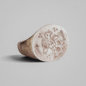 Angled view of medieval silver ring Aetos showing intaglio eagle motif and tarnished recesses