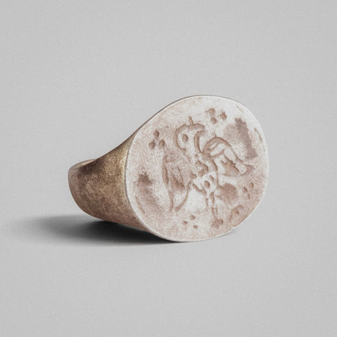 Angled view of medieval silver ring Aetos showing intaglio eagle motif and tarnished recesses