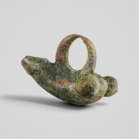 Angled view of Roman bronze fascinum pendant 'Felix' with intact suspension loop