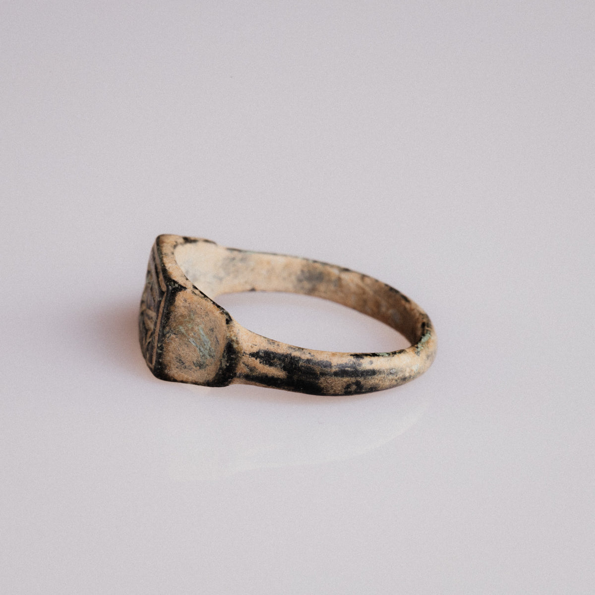 Angled view of Roman bronze signet ring Grypho with malachite green patina on shoulder