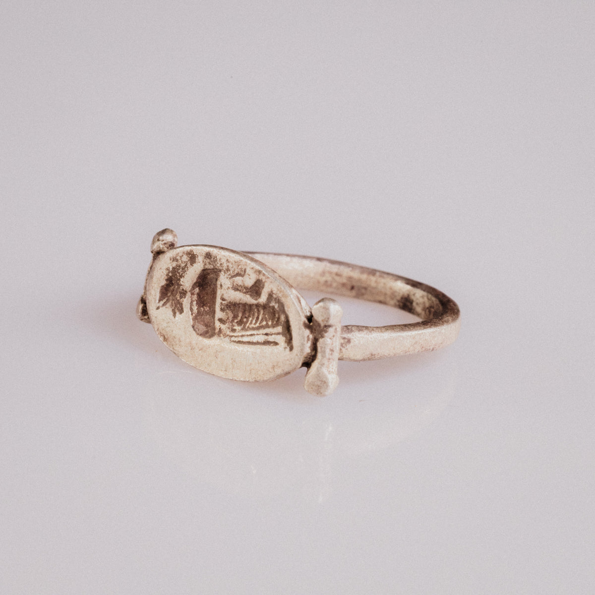 Angled view of Roman silver signet ring Numeria highlighting the intaglio drapery hatching on the bezel
