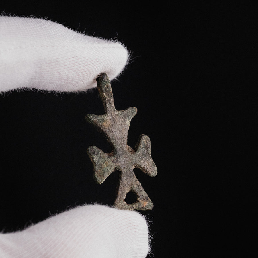 Byzantine bronze cross pendant 'Theopiste' held in gloved hand for scale, showing small size
