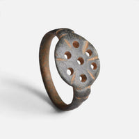 Byzantine bronze ring 'Heliona' shows its pierced circular bezel and complete hoop at an angle.