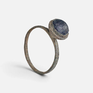 Byzantine bronze ring 'Kaloira' shows its blue setting and complete thin hoop at an angle.