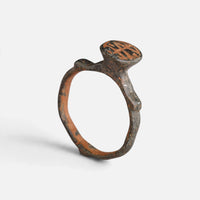 Byzantine bronze ring 'Monogrammos' shows its engraved round bezel above the complete hoop at a higher angle.
