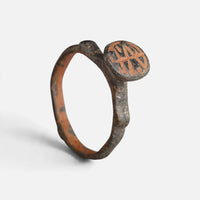 Byzantine bronze ring 'Monogrammos' shows crossed strokes on its round bezel and complete hoop at an angle.