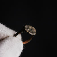 Byzantine bronze signet ring Theodoros held in gloved hand, bezel detail