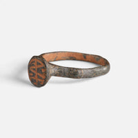Byzantine bronze ring 'Monogrammos' shows its circular bezel engraving from the opposite front angle.