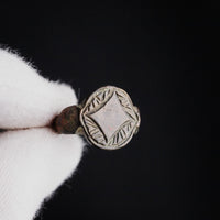 Close macro of medieval bronze ring Aldwyn quatrefoil bezel against dark background