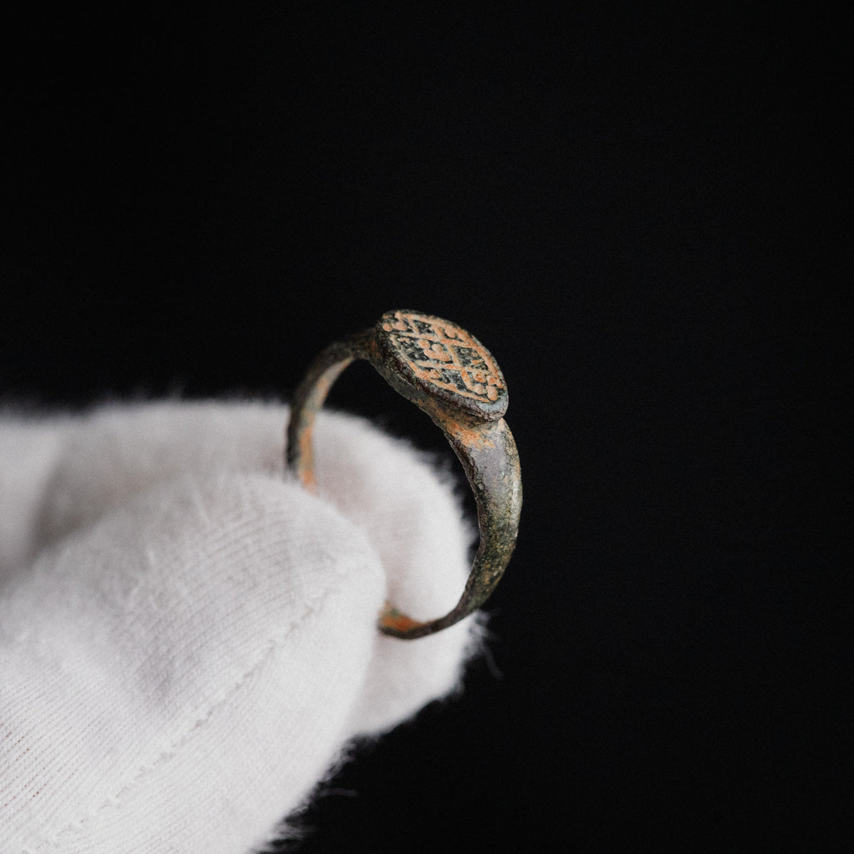 Close-up of Byzantine bronze ring 'Theodora' cross-and-dot bezel engraving on gloved hand