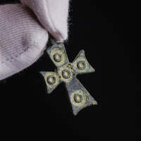 Close-up of medieval bronze cross pendant 'Okellos' showing ring-and-dot bosses in relief