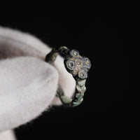 Close-up of medieval bronze ring Quintus with quatrefoil bezel held in gloved hand