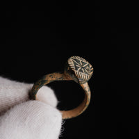 Close-up of medieval bronze ring Zvezdan star bezel highlighting engraved rays and framing