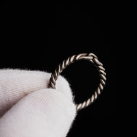 Detail crop of medieval silver ring Hravnar showing the loop terminals and transverse bar closure on white cloth