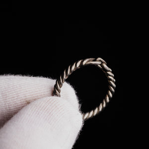 Detail crop of medieval silver ring Hravnar showing the loop terminals and transverse bar closure on white cloth