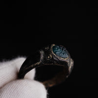 Detail macro of Volusenus glass paste intaglio showing incised foliate motif and punched dots