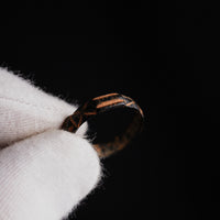 Detail of medieval bronze ring Aldric held in gloved hand, showing warm cuprite highlights