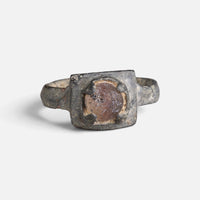 Medieval bronze ring 'Aldonza' shows its reddish oval setting and raised platform from the front.