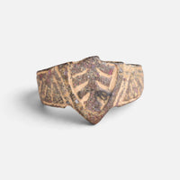 Medieval bronze ring 'Radbert' shows its shield-shaped device and incised shoulders from the front.