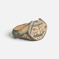 Medieval Islamic bronze ring 'Nasirun' shows its engraved bezel and decorated broad shoulder at an angle.