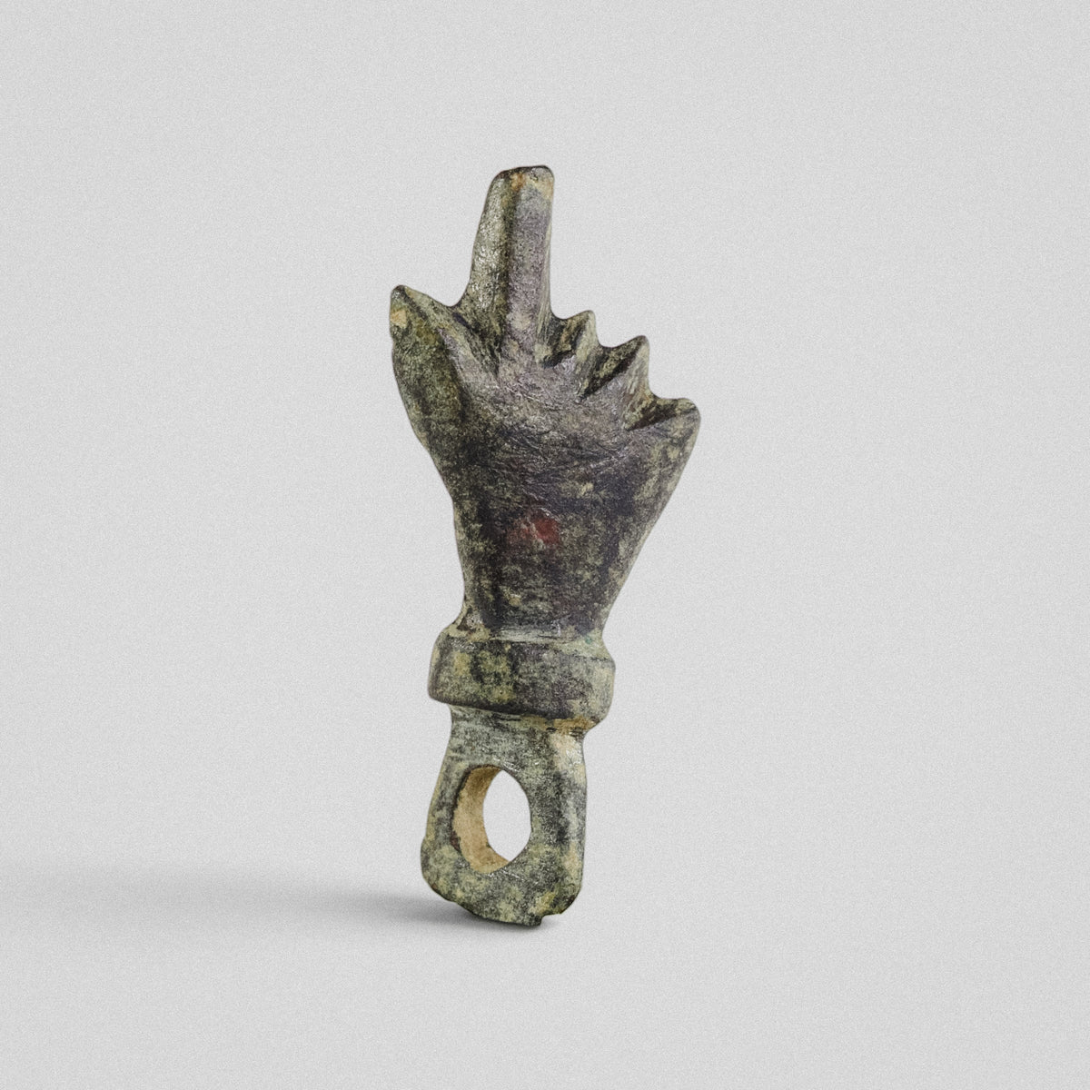Front view of Roman bronze pendant Manicula, mano fica with the thumb between the folded fingers