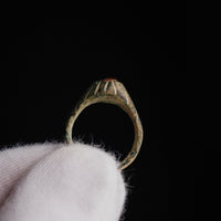 Frontal detail of medieval bronze ring Vetrona showing raised bezel profile against dark background